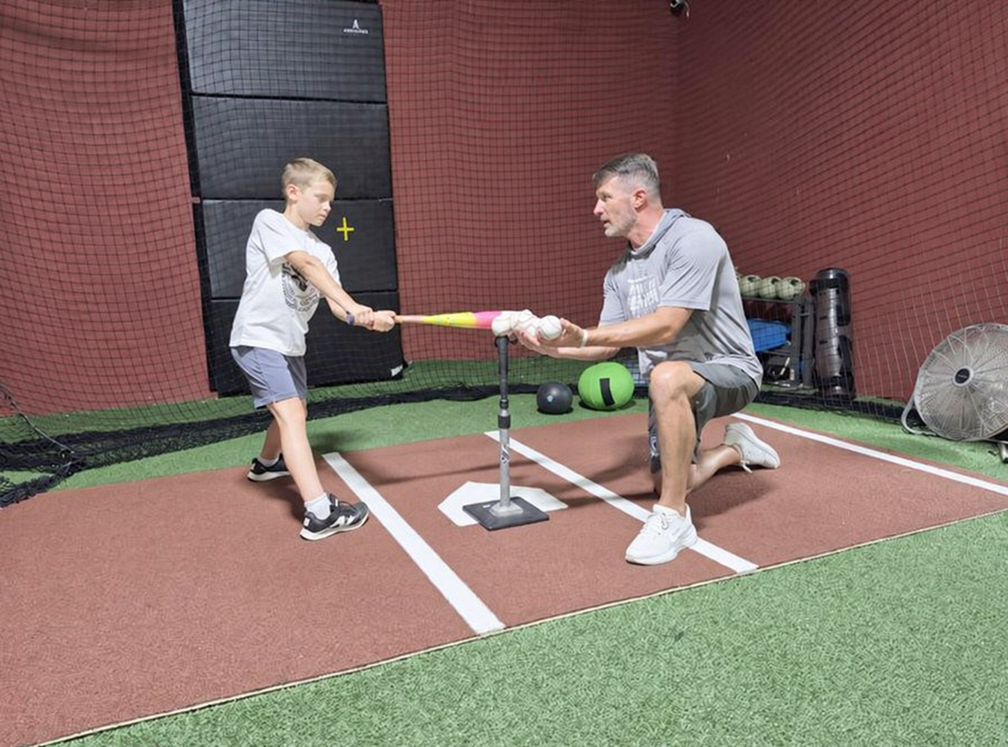 A Triple Play Sports instructor coaching a young baseball player on hitting off a tee